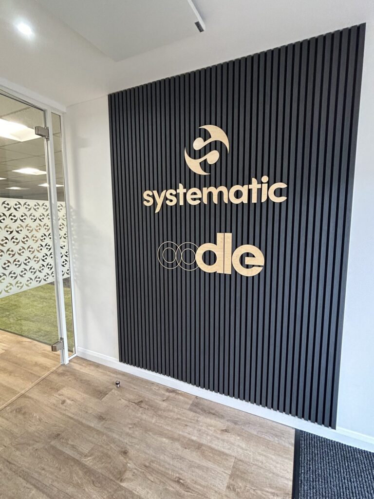 A photo of the entrance at oodle headquarters with oodle and Systematic wooden signage